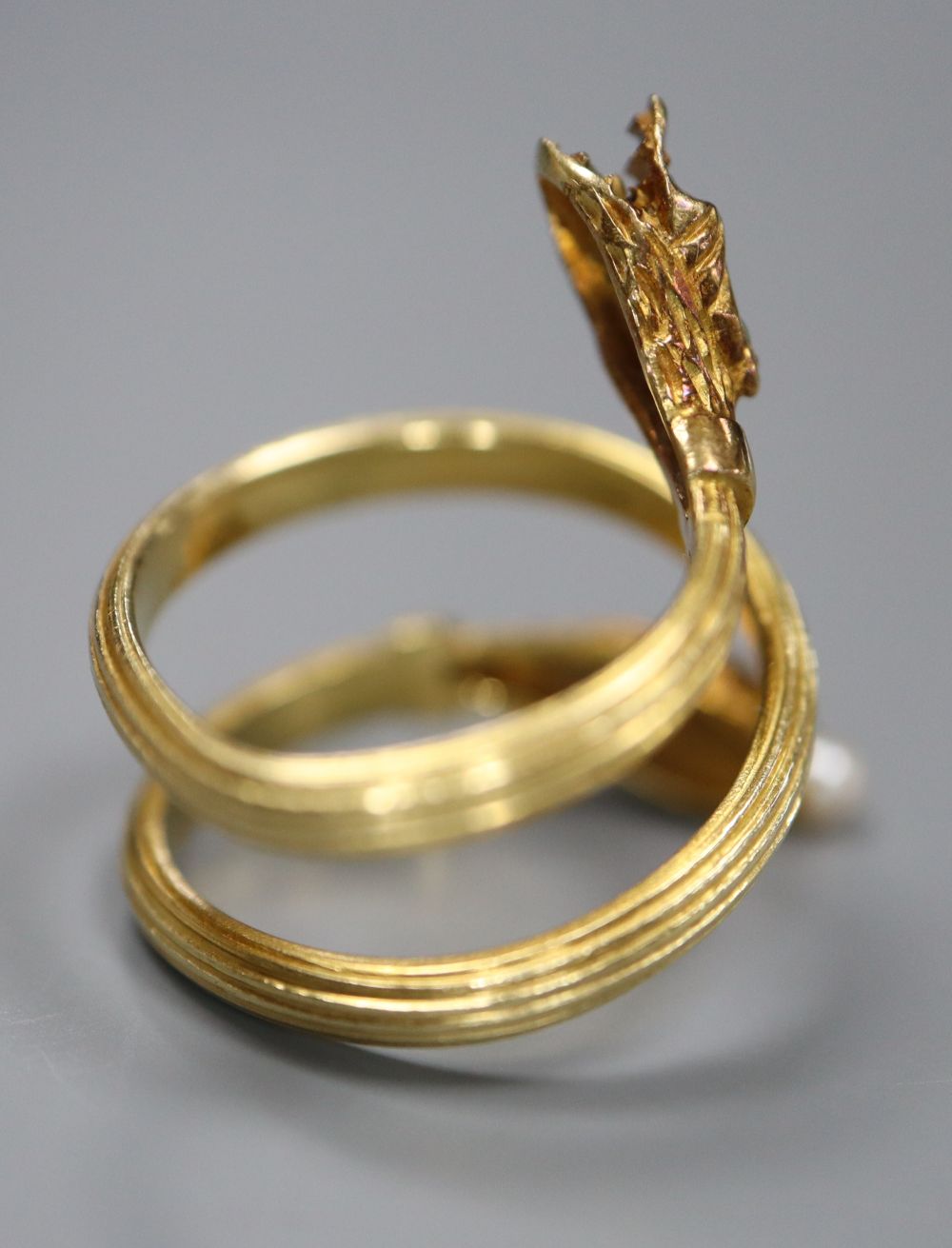 A Georgian style reeded yellow metal and gem set twin headed serpent ring,